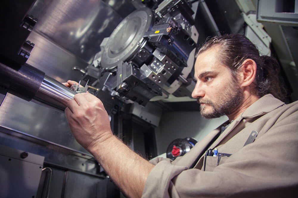 Technicien procédant à l’usinage de précision sur tour CNC pour le remplacement d’une pièce mécanique